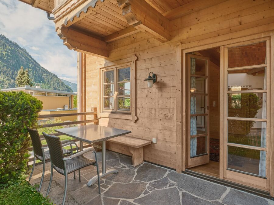 Die sonnige Terrasse des Chalets Alpen-Synfonie, ausgestattet mit Holztisch und Stühlen, bietet einen atemberaubenden Blick auf die umliegenden Berge in Mayrhofen.