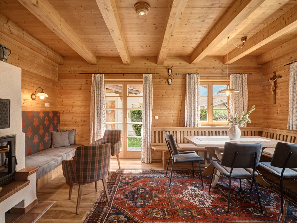 Gemütlicher Wohnbereich im Chalet Alpen-Synfonie mit Holzdecke, Kamin und traditionellem tiroler Interieur.
