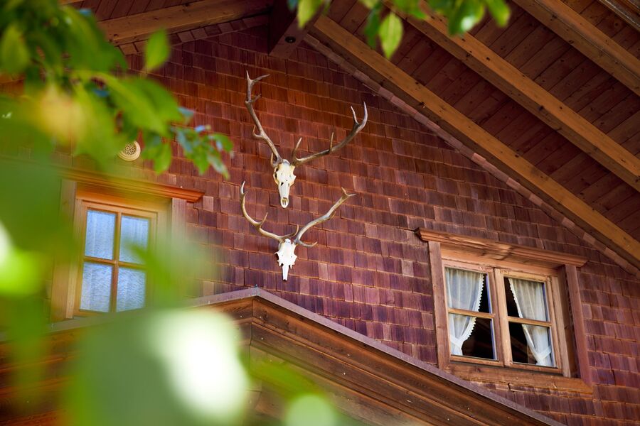 Zwei antike Hirschgeweihe schmücken die hölzerne Fassade des traditionellen Tiroler Chalet Nostalgie in Mayrhofen.