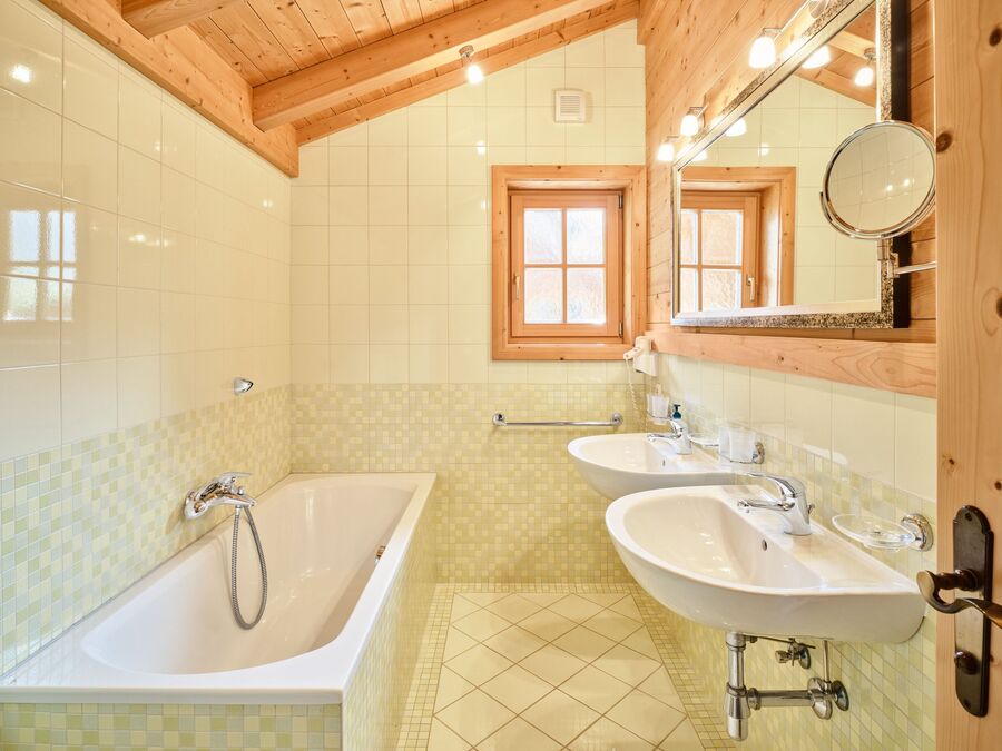 Großes Badezimmer im Chalet Alpen-Synfonie, mit Badewanne, zwei Waschbecken und Holzdekor.