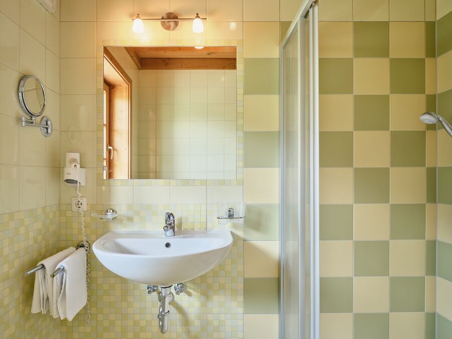 Helles Badezimmer im Chalet Alpen-Synfonie, mit Dusche, stilvollen Fliesen und einer funktionalen Ausstattung für höchsten Komfort im alpinen Stil.