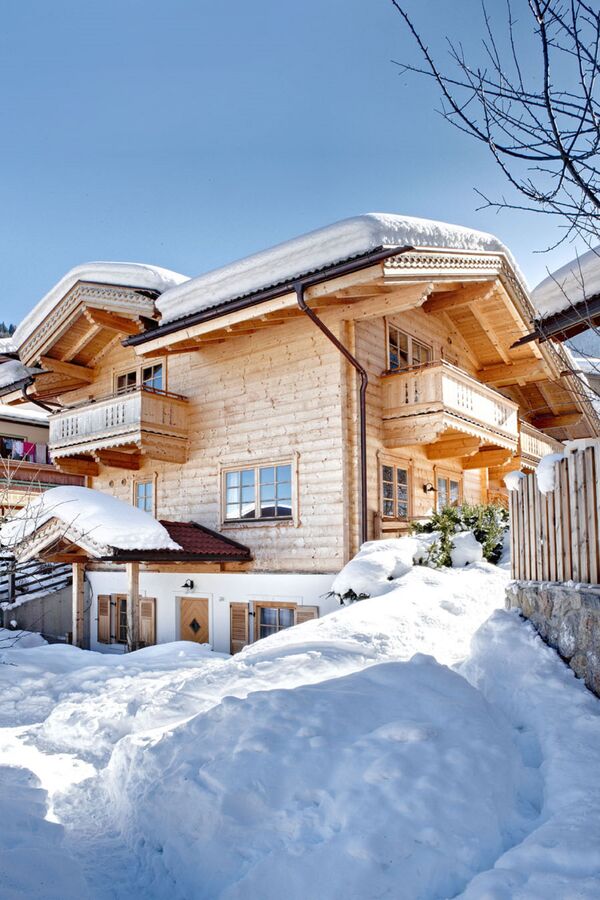 Die Huber Chalets in Mayrhofen, Zillertal, im Winter, mit verschneiten Dächern und blauen Himmel im Hintergrund.
