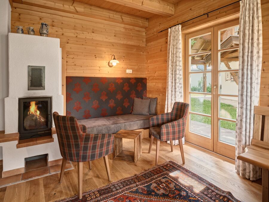 Gemütlicher Wohnbereich im Chalet Alpen-Synfonie mit Holzdecke, Kamin und traditionellem tiroler Interieur.