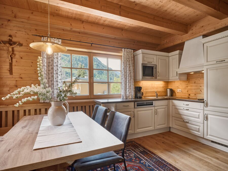 Moderne, voll ausgestattete Küche im Chalet Alpen-Synfonie, mit Holzdekor und Blick auf die Berge im Zillertal.