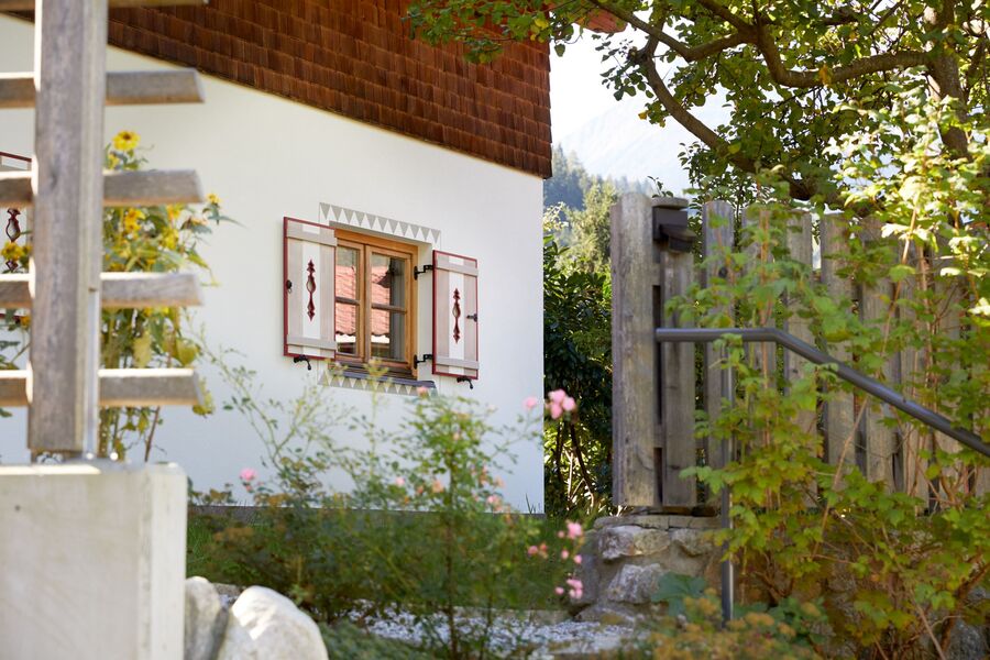 Stimmungsvolle Sommerlandschaft mit grünen Pflanzen und einem traditionell gestalteten Chalet Nostalgie, umgeben von den Zillertaler Alpen.