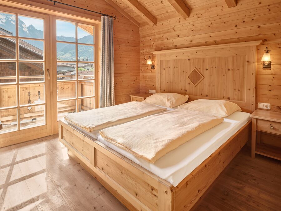 Schlafzimmer im Chalet Alpen-Synfonie mit Holzausstattung und einem beeindruckenden Ausblick auf die Berge im Zillertal.