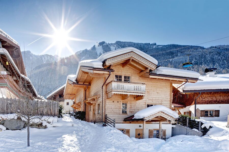 Ein sonniger Wintertag bei den Huber Chalets in Mayrhofen, mit verschneiten Dächern und Bergen im Hintergrund.