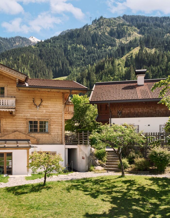 Charmante Huber Chalets mit grünem Garten, umgeben von Bergen im Zillertal. Ideal für einen erholsamen Urlaub in den Tiroler Alpen.